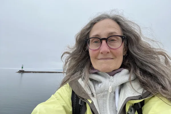 person with gray hair and black glasses smiling