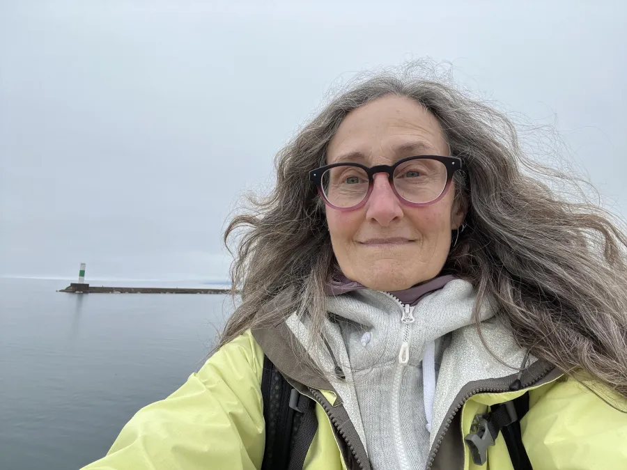 person with gray hair and black glasses smiling